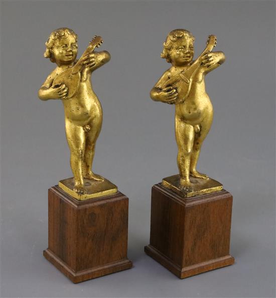 A pair of 17th century Italian gilt metal figures of putto playing mandolins, overall height 7.75in.